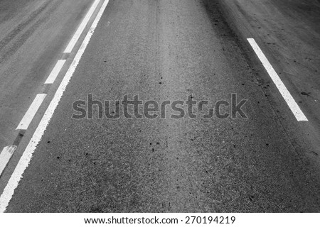 Asphalt road with dividing lines and tire tracks. Background photo with perspective effect