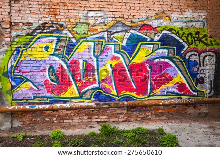 Saint-Petersburg, Russia - May 6, 2015: Abandoned urban courtyard with colorful abstract graffiti text pattern on old brick wall. Vasilievsky island, Central part of St. Petersburg