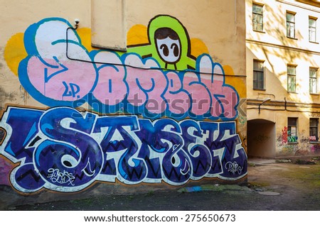 Saint-Petersburg, Russia - May 6, 2015: Abandoned urban courtyard with colorful abstract graffiti text patterns on old yellow wall. Vasilievsky island, Central part of St. Petersburg