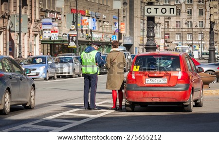 Saint-Petersburg, Russia - April 24, 2015: Russian traffic police inspector checks documents of a stopped inexperienced driver on a roadside in a big city