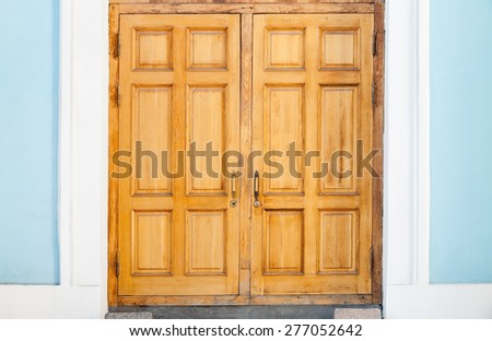Closed old wooden door in blue white wall, classical architecture background texture