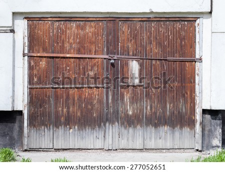 Old locked wooden gate in white concrete wall of an ordinary living house