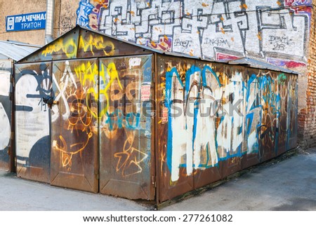 Saint-Petersburg, Russia - May 6, 2015: Old rusted locked abandoned garage with chaotic grungy graffiti. Vasilievsky island, Central old part of St. Petersburg city