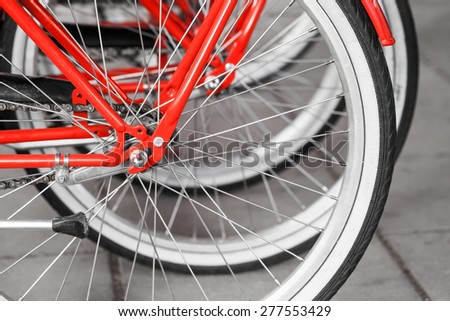 Parked red street bicycles for rent, rear wheels fragment, selective focus with shallow DOF