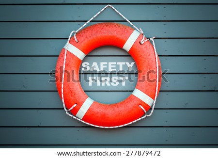 Safety first. Red lifebuoy hanging on blue wooden wall of a port building with the text label