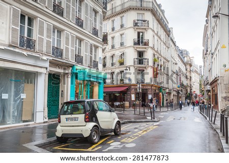 Paris, France - August 10, 2014: small white Smart car stands on the street in Paris, tourists walk on Rue St. Andre Des Arts