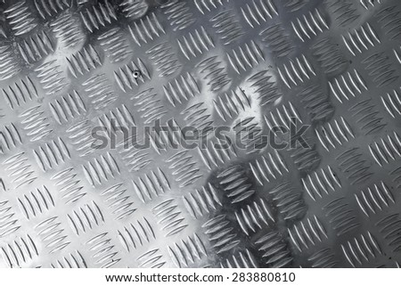 Dark gray shining metal floor surface with industrial diamond plate relief pattern