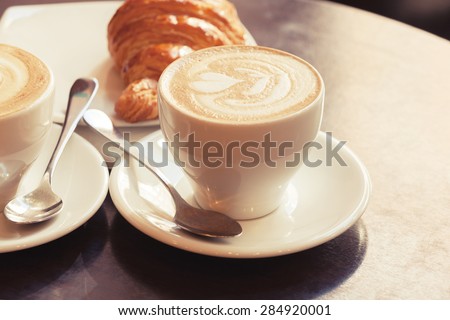 milk foam with cups  with coffee on cappuccino croissant.  cups Cappuccino Two of vintage stands