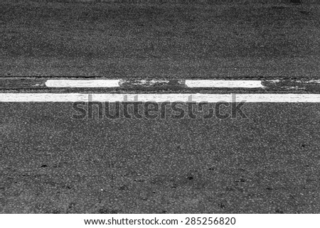 Asphalt road with dividing line and tire tracks. Abstract transportation background with selective focus