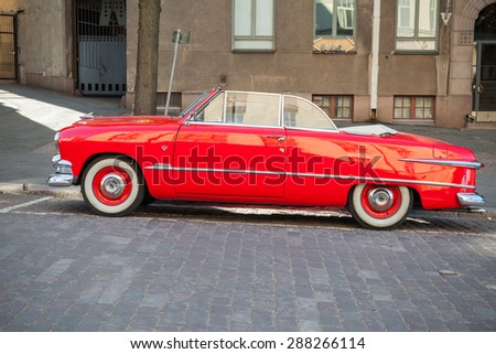 Helsinki, Finland - June 13, 2015: Old red Ford Custom Deluxe Tudor car is parked on the roadside. 1951 year modification with convertible roof, side view