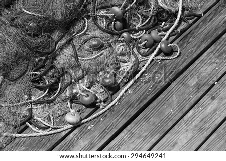 Fishing net laying on wooden pier, black and white photo