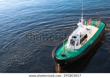 Small pilot boat with green deck on a sea water