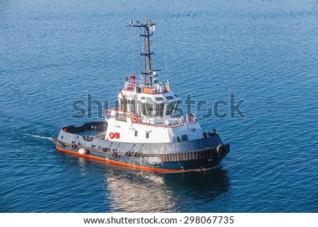 Tug boat with white superstructure and dark blue hull underway on sea water