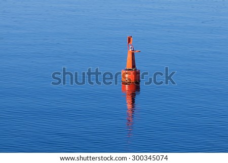 Red modern navigation buoy floating on still sea water