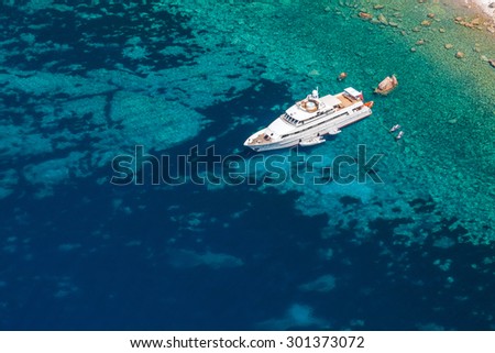 Luxury white pleasure yacht anchored near rocky coast of Corsica island, birds eye view