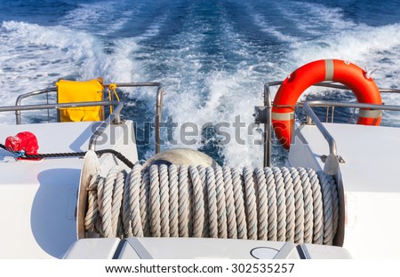 Red lifebuoy and winch with rope on stern of fast safety rescue boat
