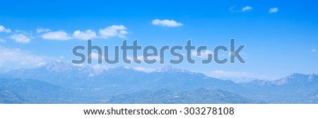 Panoramic natural photo background with mountains under bright cloudy sky. Corsica, France