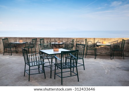 Open space seaside restaurant interior with metal chairs under blue sky