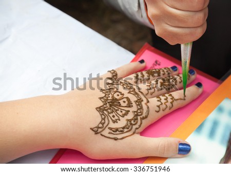 Saint-Petersburg, Russia - July 19, 2015: Brown henna paste or mehndi application on woman hand, traditional Indian natural skin decoration or bio-tattoo