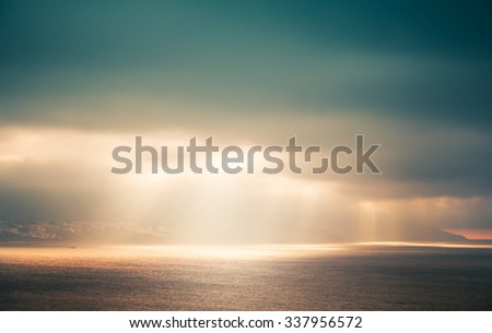 Atlantic ocean landscape, evening sunlight goes through dark cloudy sky. Retro style, colorful tonal correction photo filter effect