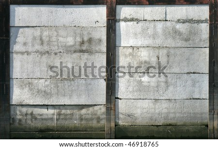 Abstract texture of an old concrete mooring wall with black rusted metal framing