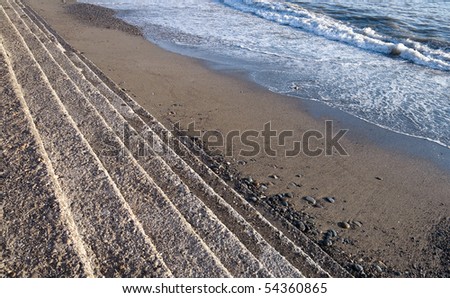 Black Sea coastline abstract background with concrete footsteps, sand and seawater