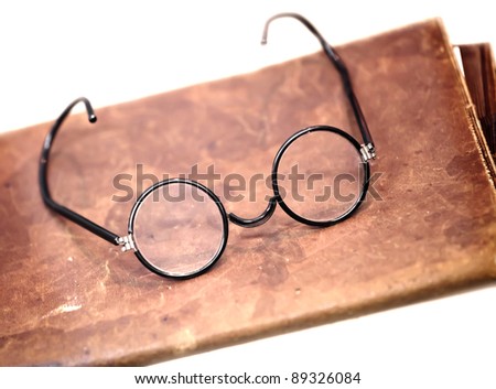 Old glasses on the leather folder isolated on white