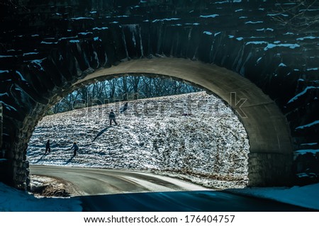 snow sledding down the hill seen under the bridge tunnel