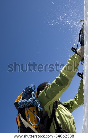 A climber uses his ice picks to assist him in reaching the top of a steep cliff.