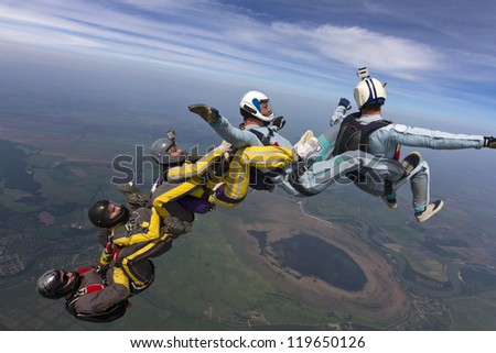 Five skydivers free-fall in the figure.
