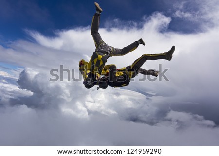 Three skydiver in free-fall in the clouds.
