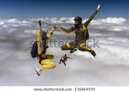 Three sports parachutist build a figure in free fall.