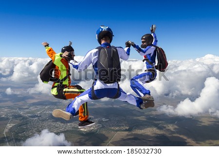 Three sports parachutist build a figure in free fall.