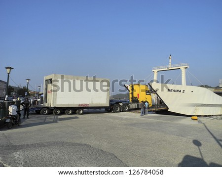 SKIATHOS, GREECE - OCTOBER 04: Unloading of a heavy vehicle with trailer from freighter in the harbour of the island, different goods can only delivered by ship, October 04, 2012 in Skiathos, Greece