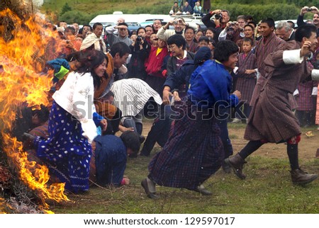 JAKAR, BHUTAN - SEPTEMBER 26: unidentified people running through an open fire at the yearly fire and smoke ceremony to cleans of sin in Thangbi Lakhang on September 26, 2007 in Jakar, Bhutan