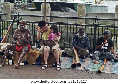 SYDNEY, AUSTRALIA - FEBRUARY 08: Unidentified tourists and aborigine street musicians playing on their traditional didgeridoos on Circular quay on February 08, 2008 in Sydney, Australia