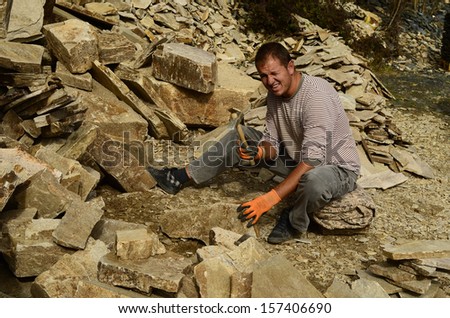SMOLYAN, BULGARIA - OCTOBER 02: Unidentified man working with hammer for stone slabs, a traditional occupation for building material for home and garden, on October 02, 2013 in Smolyan, Bulgaria