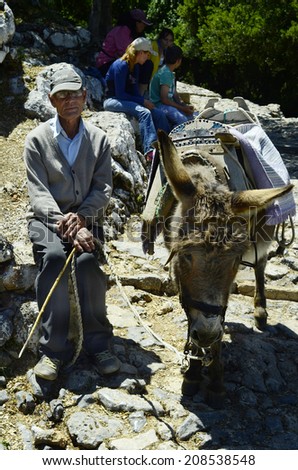 PSYCHRO, GREECE - MAY 23: Unidentified man with donkey waiting for tourists to carry them to the Diktaean cave the mysthic birth place of Zeus on Crete island; on May 23, 2014 in Psychro, Greece