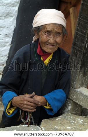 JAKAR, BHUTAN - SEPTEMBER 26: unidentified old woman with rosary and traditional wrap skirt named Kira on the way to the Jakar Dzong to pray on September 26, 2007 in Jakar, Bumthang, Bhutan