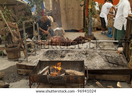 Austria, cooks on open fireplace roasted pig by medieval city festival