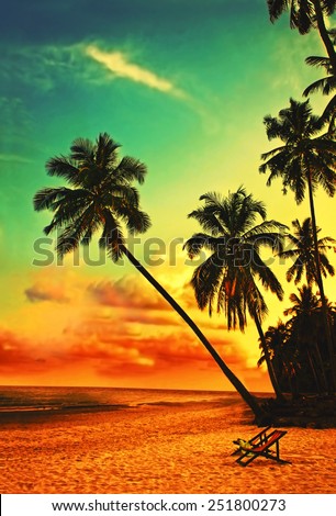 Beautiful tropical beach with silhouettes of palm trees at sunset. Travel background with retro vintage instagram filter.