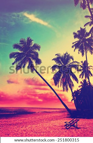 Beautiful tropical beach with silhouettes of palm trees at sunset. Travel background with retro vintage instagram filter.