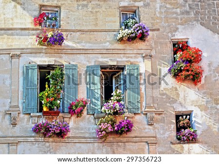 Typical facade of the old Provencal retro house with windows and wooden shutters decorated with colorful fresh flowers in Provence, Cote d\'Azur, France