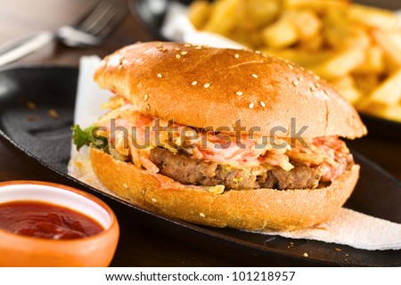 Hamburger on metallic plate with ketchup and French fries (Selective Focus, Focus on the front of the hamburger)
