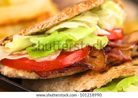 Closeup of fresh homemade BLT (bacon, lettuce and tomato) wholewheat pita sandwich (Selective Focus, Focus on the front of the upper pita stuffing)