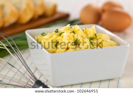 Scrambled eggs with green onion in bowl with beater on the side (Selective Focus, Focus one third into the bowl)