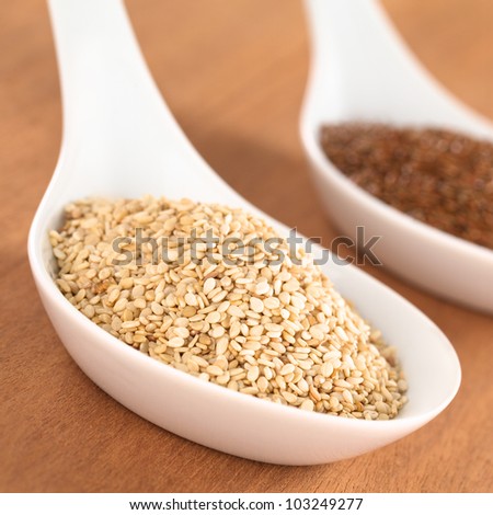 Sesame seeds and brown flax seeds on ceramic spoon (Selective Focus, Focus one third into the sesame seeds)