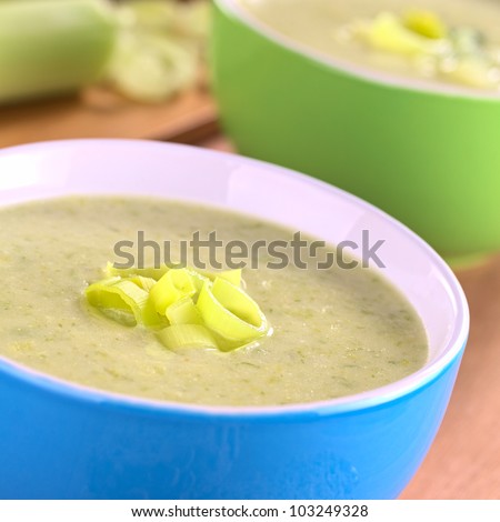 Two bowls of fresh homemade creamy leek soup garnished with leek rings (Selective Focus, Focus on the leek rings on the top of the soup)