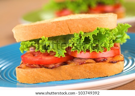 Fresh homemade BLT (bacon lettuce and tomato) sandwich on blue plate (Selective Focus, Focus on the front of the first sandwich)