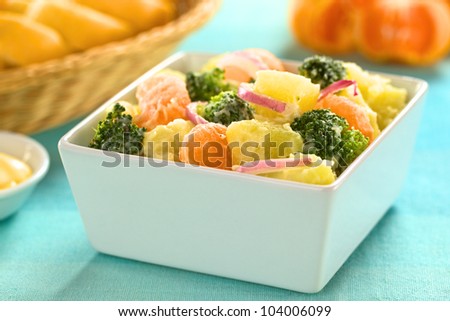 Bowl full of fresh salad of potato, broccoli, mandarin and onion with mayonnaise (Selective Focus, Focus on the mandarin, broccoli and the potato in the front)